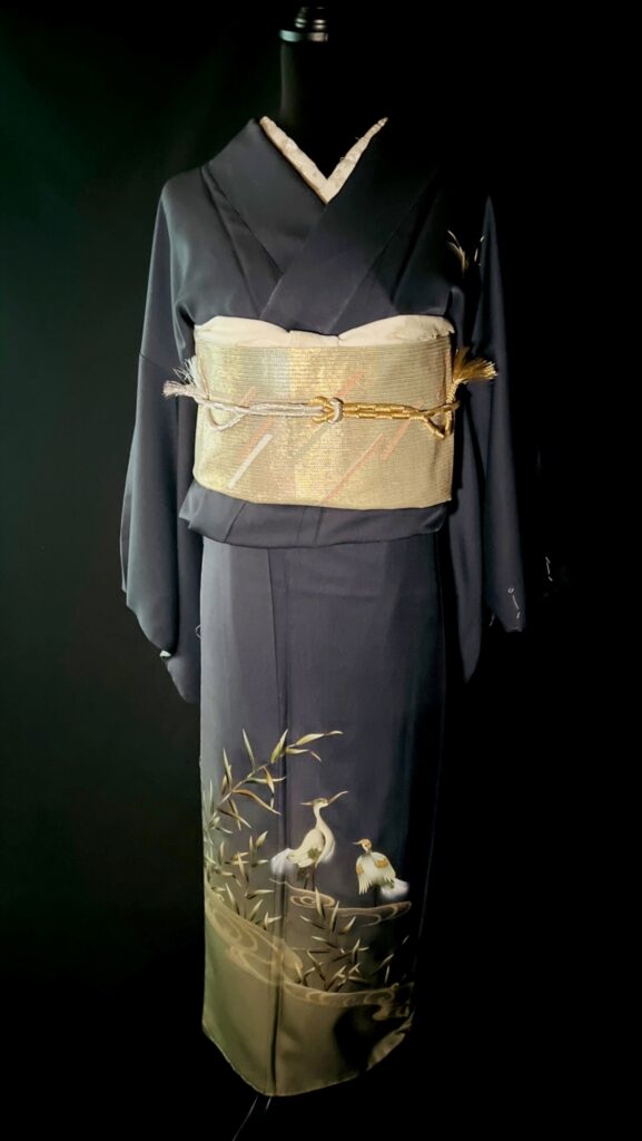 藍色の訪問着の全身写真。裾に鷺と水辺の景が描かれた意匠