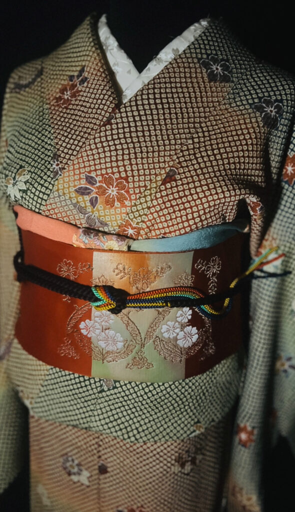 総絞りの小紋の帯まわりアップ（朱×金の帯と黒の帯締め、丸文様）