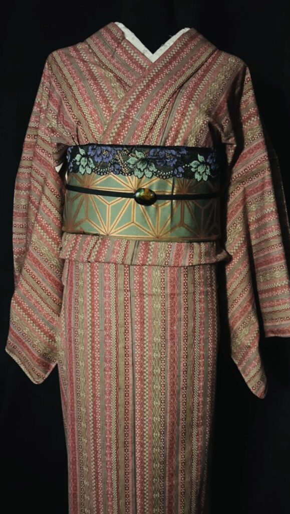 赤茶の縞模様のウール着物に、緑×金の幾何学柄の帯を合わせた全身コーデ（家紋なし）