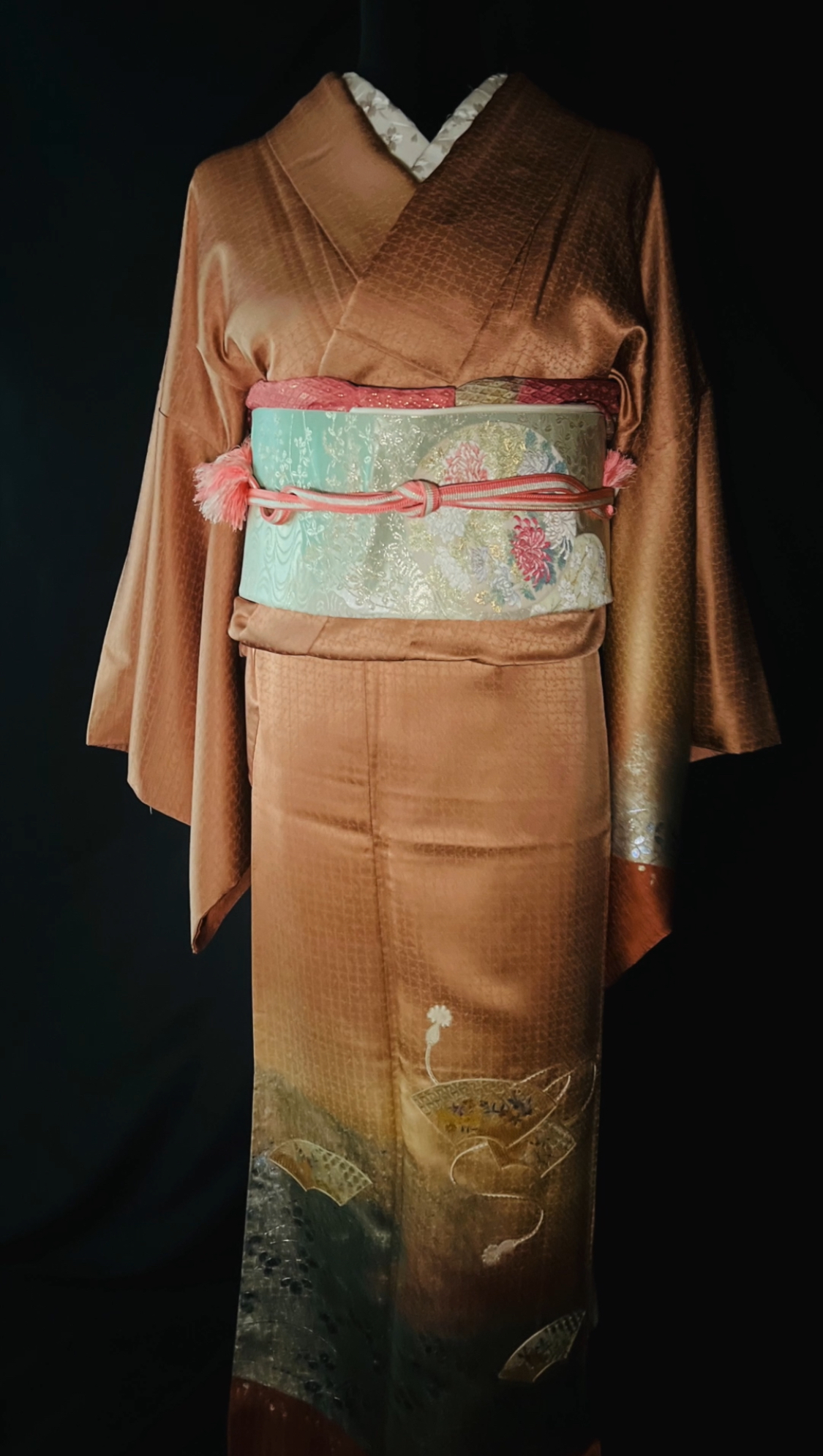 橙のグラデーションに扇文様が描かれた訪問着に淡い帯を合わせた着姿