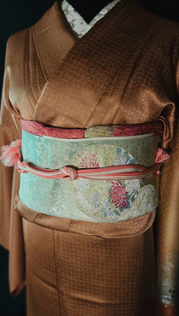 橙の訪問着と淡いグリーンの帯、ピンクの帯締めの組み合わせ