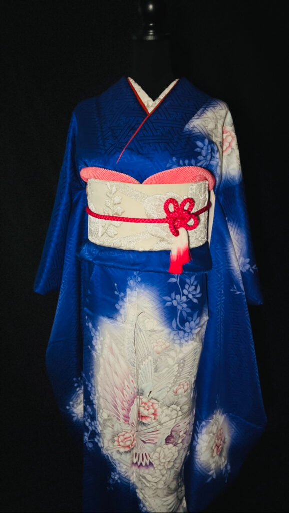 深い青の振袖に鶴と花模様が描かれた華やかな着姿