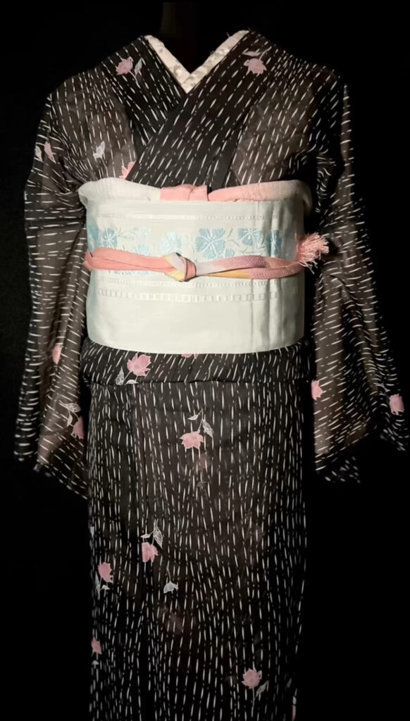透け感のある黒の紗着物と花柄の半幅帯を合わせた上半身写真