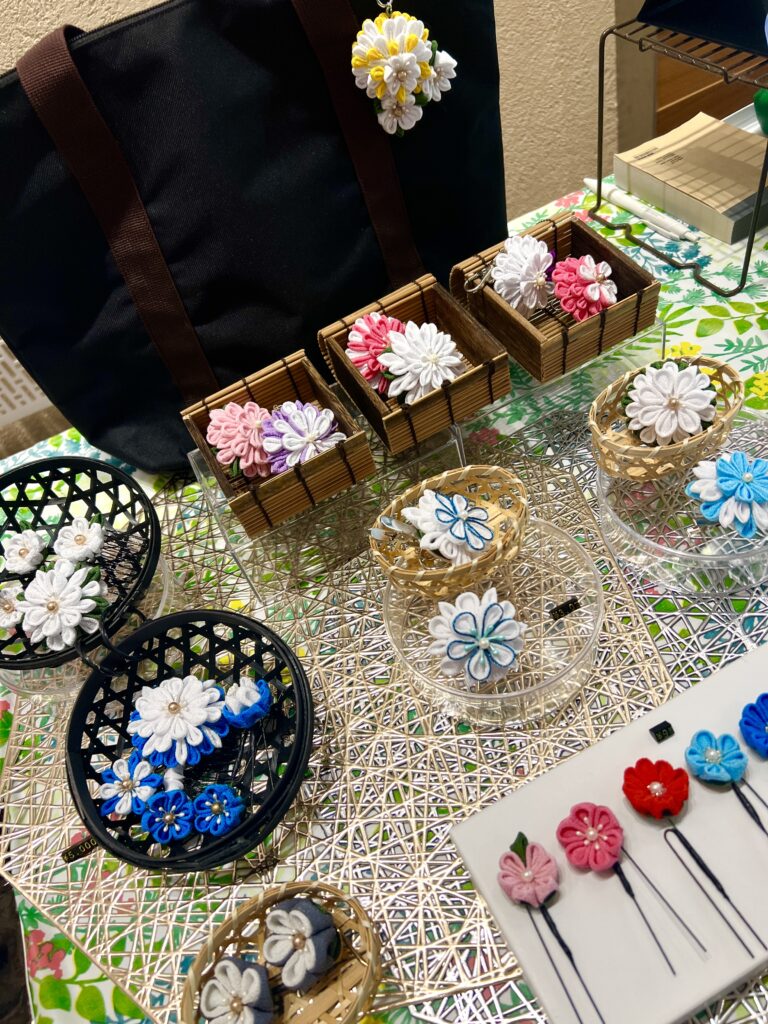 atelier aloのつまみ細工作品。クリップやヘアアクセサリーを中心に、色とりどりの花モチーフを展示した様子。