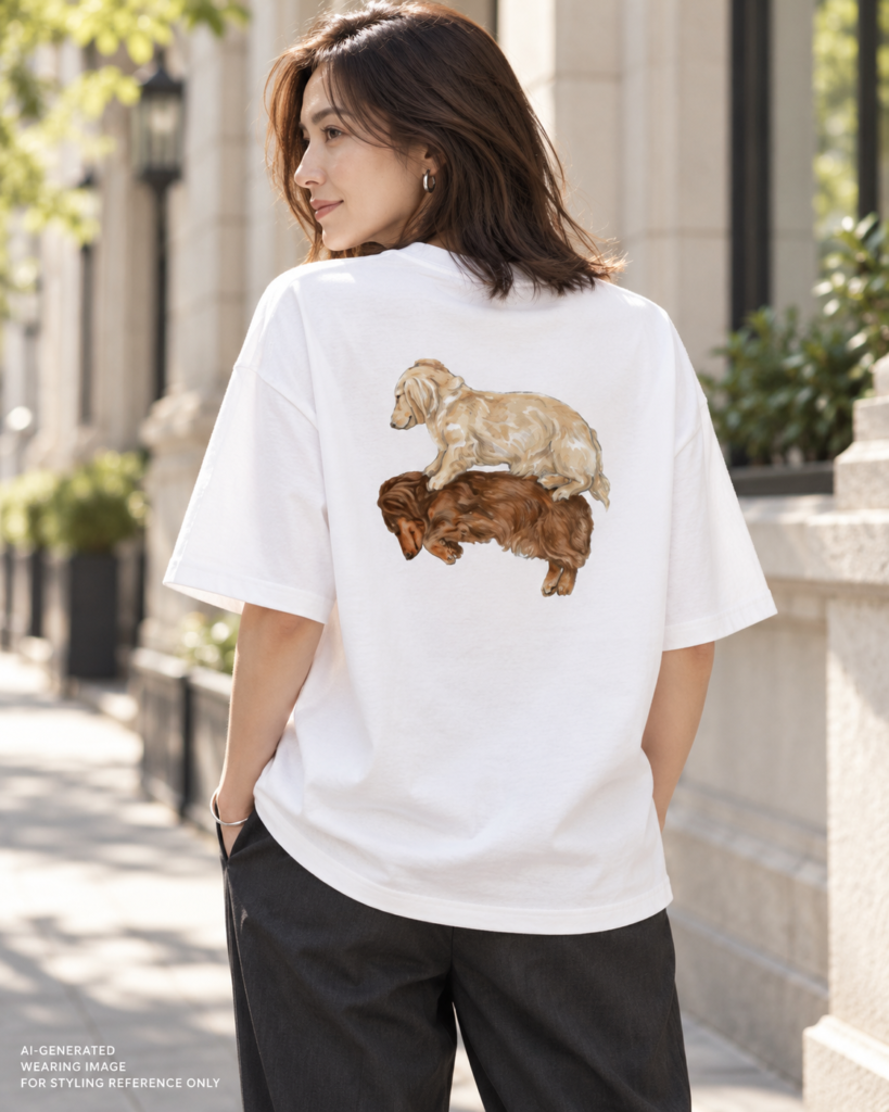 AI-generated styling image of a woman looking over her shoulder, showing the Napping Dachshunds back print on a white oversized T-shirt paired with dark gray trousers.