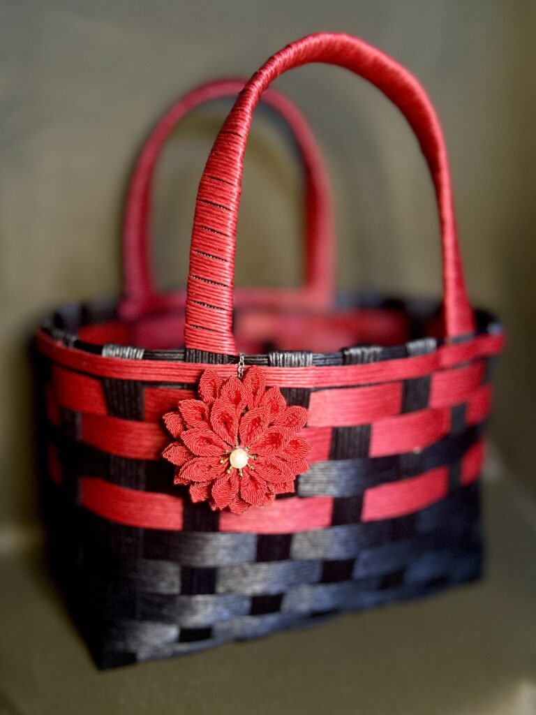 赤と黒のクラフトバンドを編み、赤いつまみ細工の花を添えたatelier aloの和モダンバッグ「朱墨」。