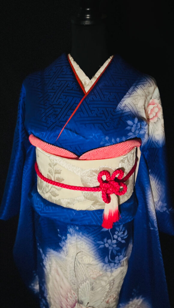青い花柄振袖に淡い生成り系の帯と赤い帯揚げと帯締めを合わせたコーディネート